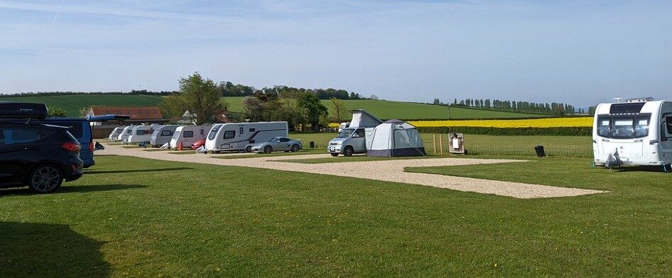 Pitches with caravans and a tent under a wide sky