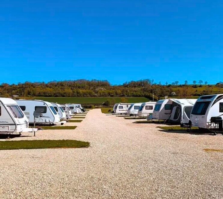 A motorhome on a level grass pitch with electric hook-up